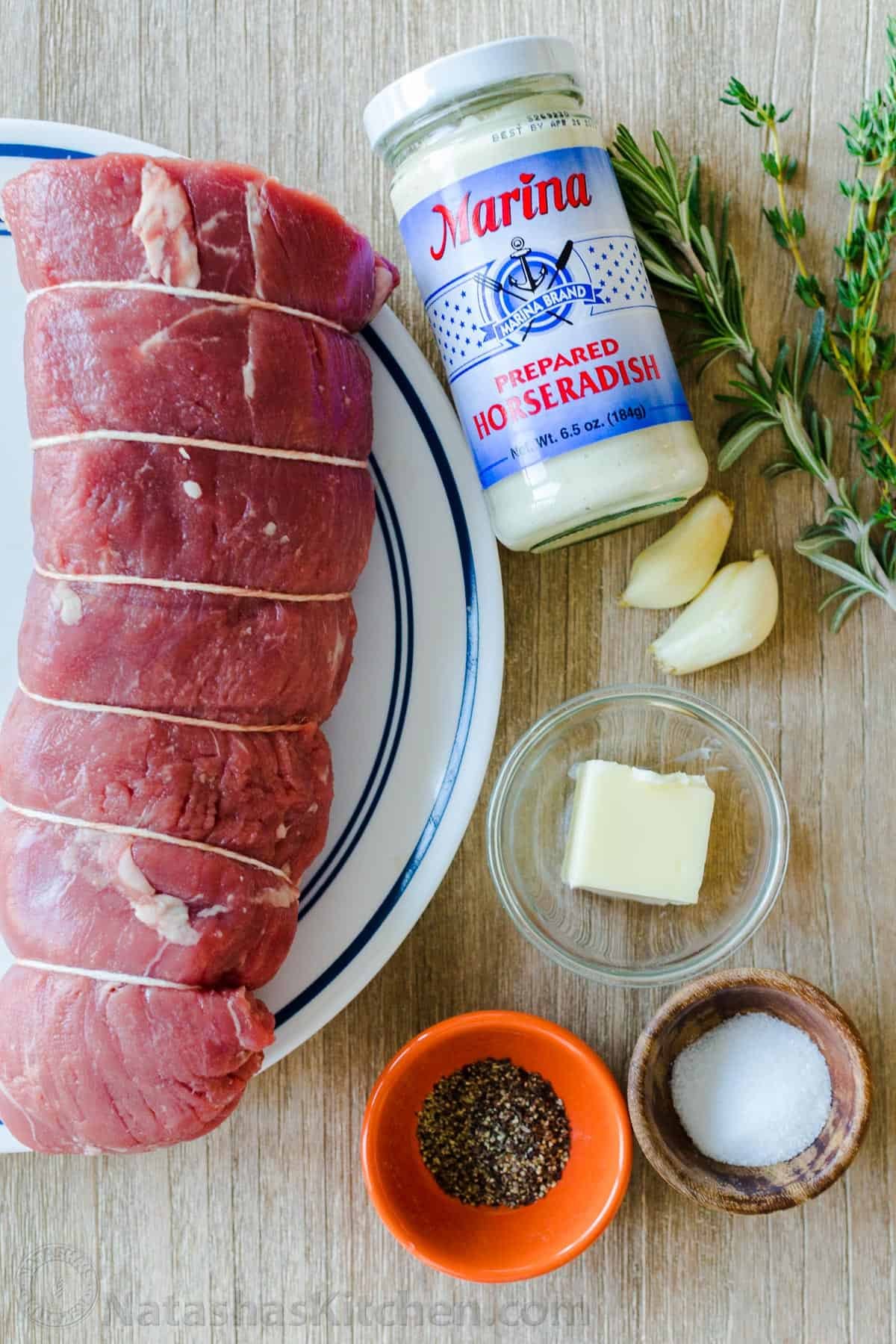 Roasted Beef Tenderloin is a showstopper! This tried and true easy method produces melt-in-your-mouth tender beef. How to trim, tie and cook beef tenderloin. #beeftenderloin #beeftenderloinrecipe #roastedbeeftenderloin #beef #steak #valentinesdaydinner #valentinesdayrecipes #natashaskitchen #dinner #tenderloin Ingredients for beef tenderloin recipe with filet of beef, garlic, butter, horseradish sauce, thyme and rosemary