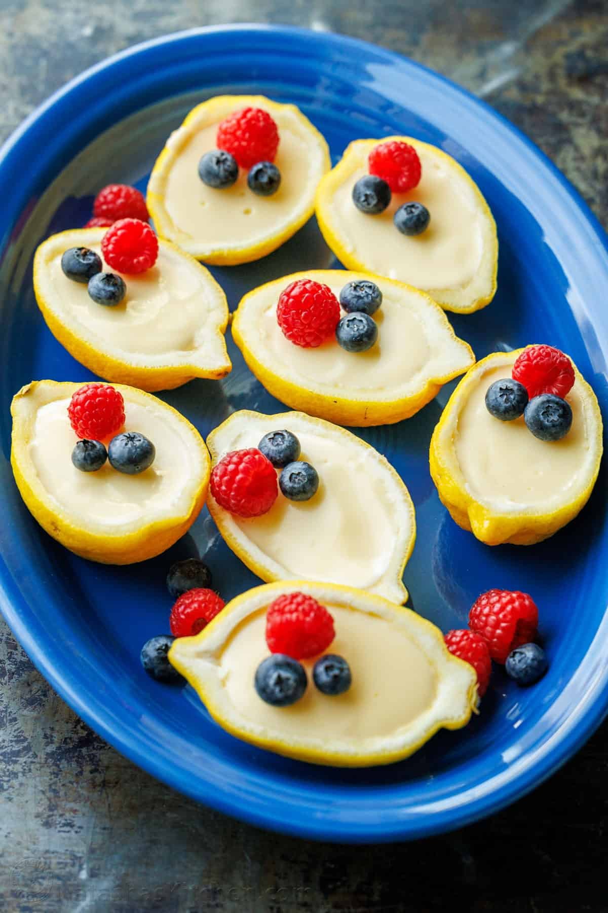 My 3-ingredient Lemon Posset recipe is a velvety smooth lemon custard. It's the perfect make-ahead dessert and cooks in 5 minutes on the stove Blue plate serving lemon posset desserts topped with raspberries and blueberries