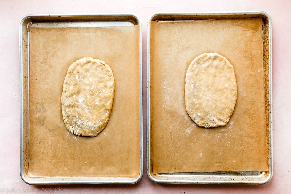 two baking sheets each with a slab of biscotti dough before baking