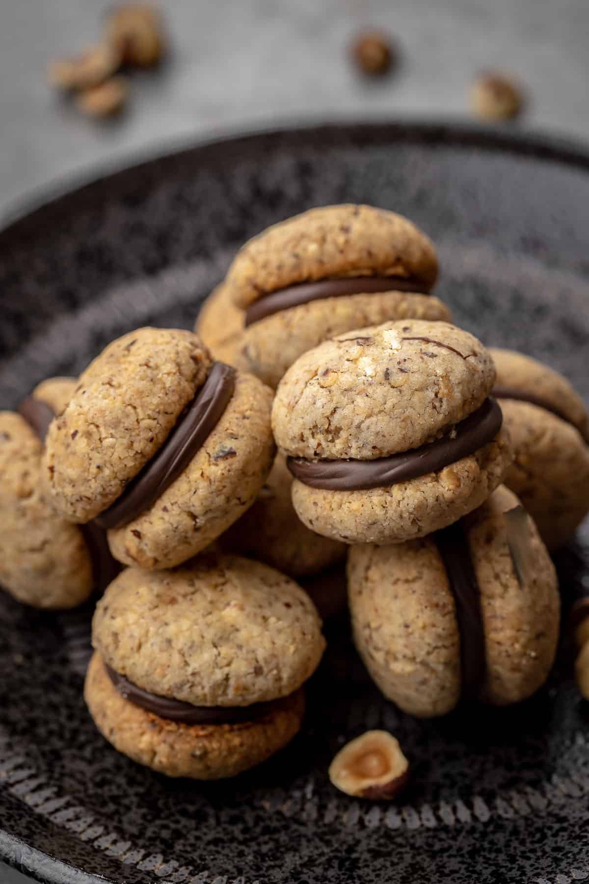 Italian Cookies Baci di Dama a.k.a. lady kisses are filled with chocolate. These cookies are beautiful and irresistibly good. #Italiancookies #bacididama #cookies #sandwichcookies Italian cookies stacked on a platter