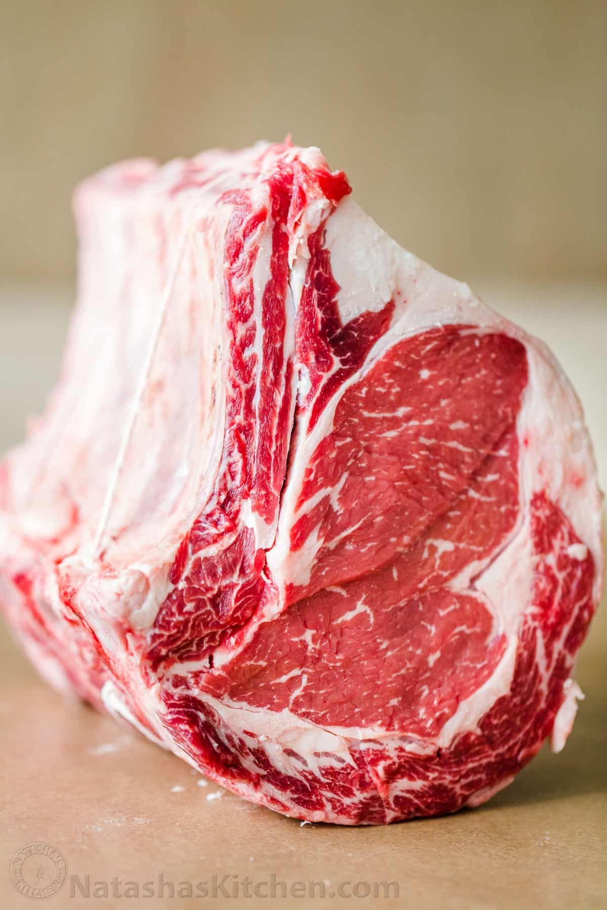 Everything you need to know to purchase the perfect Prime Rib Roast, from beef quality grades, bone-in vs boneless, and how big of a roast you need. Bone-in prime rib tied with string