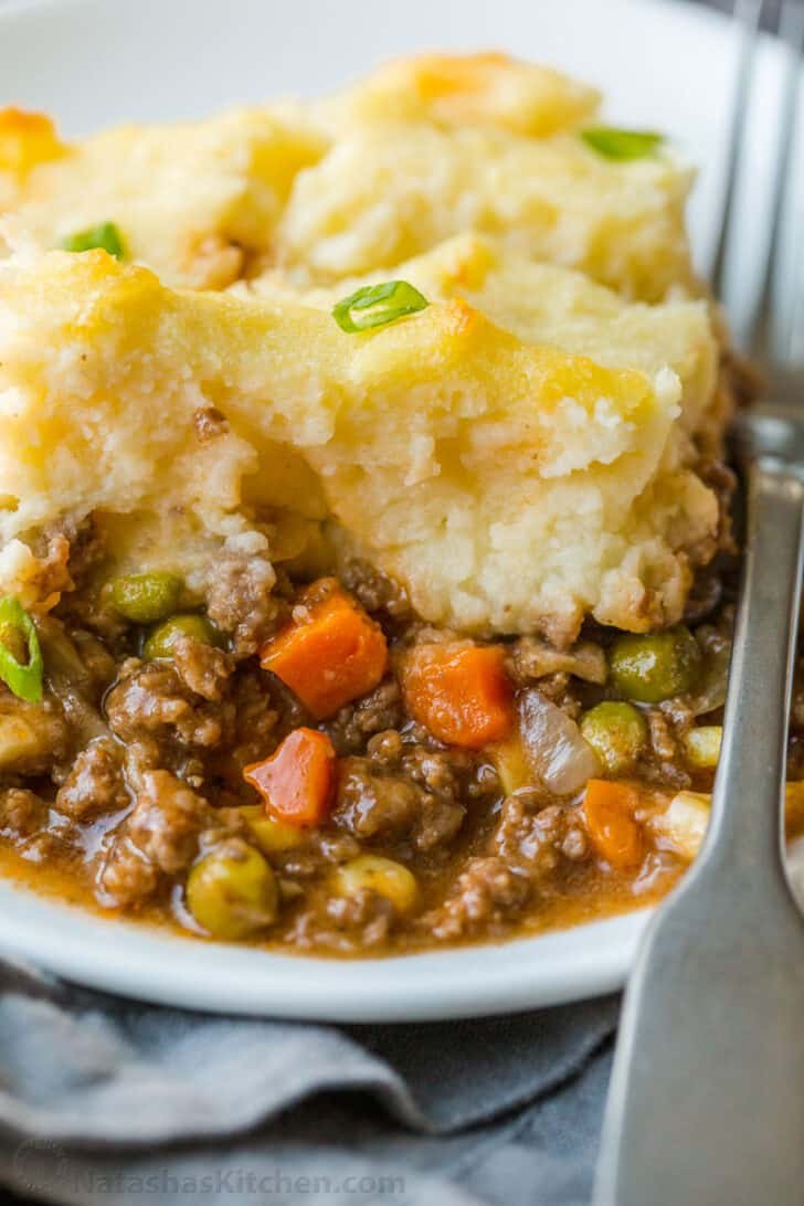 A homey and comforting Shepherd's Pie recipe with a meat and vegetable gravy sauce under a crown of creamy parmesan mashed potatoes. Slice of Shepherd's Pie served on a plate