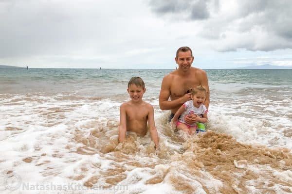 A father and his two children standing in the ocean