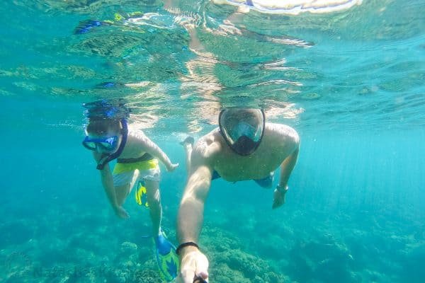 A father and son swimming underwater with scuba gear 