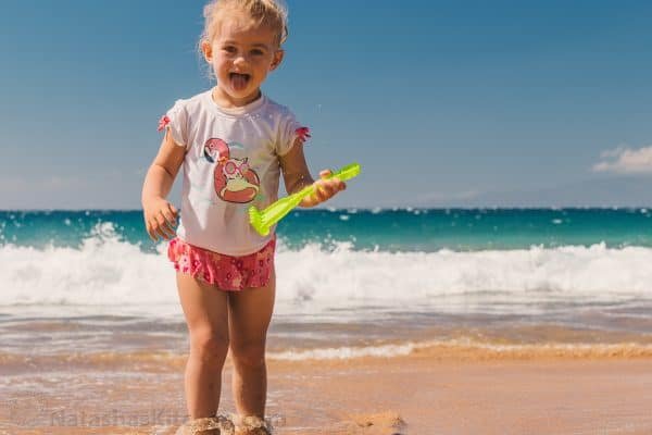 A little girl playing at the ocean with a plastic toy rake