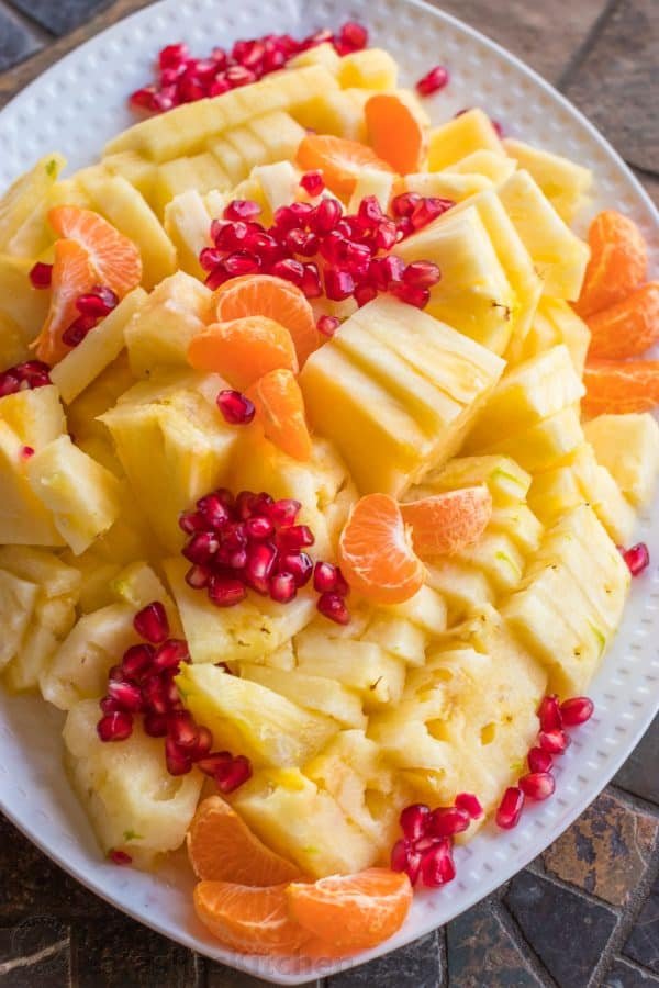 Cut up pineapple, peeled mandarins and pomegranate seeds on a plate