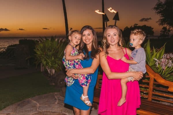 Natasha holding her daughter and a woman holding a child standing next to her 
