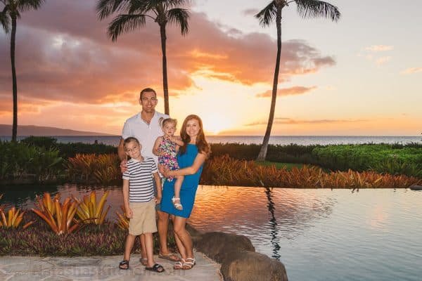 A family standing at the beach at sunset