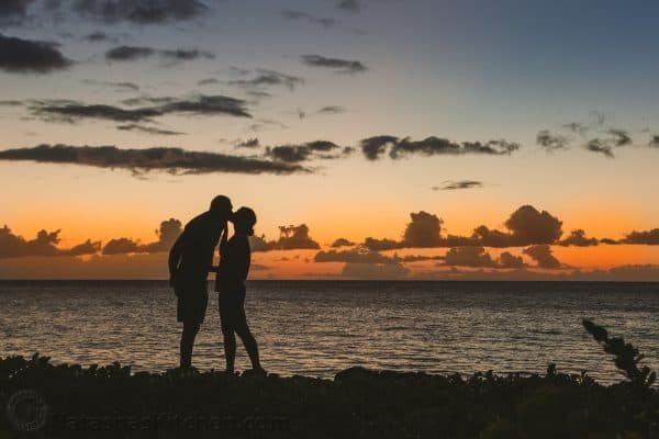 The shadow of a couple kissing at the beach at sunset