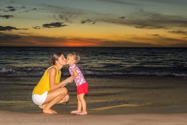 Natasha kissing her daughter on the beach at sunset