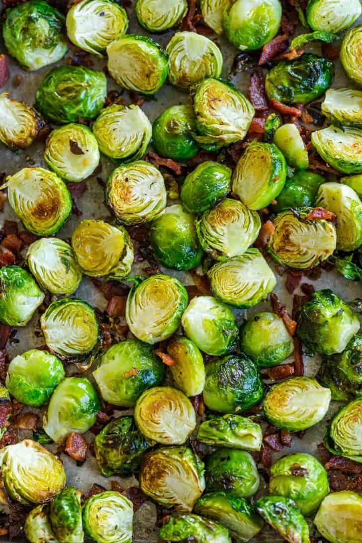 Roasted Brussels Sprouts are tender and caramelized with crisp edges. Baked Brussels sprouts are an easy, excellent side dish with just 5 ingredients. #brusselssprouts #roastedbrusselssprouts #brusselssproutsrecipe #sidedish #natashaskitchen #brusselsprouts Roasted Brussels sprouts on baking sheet with bacon