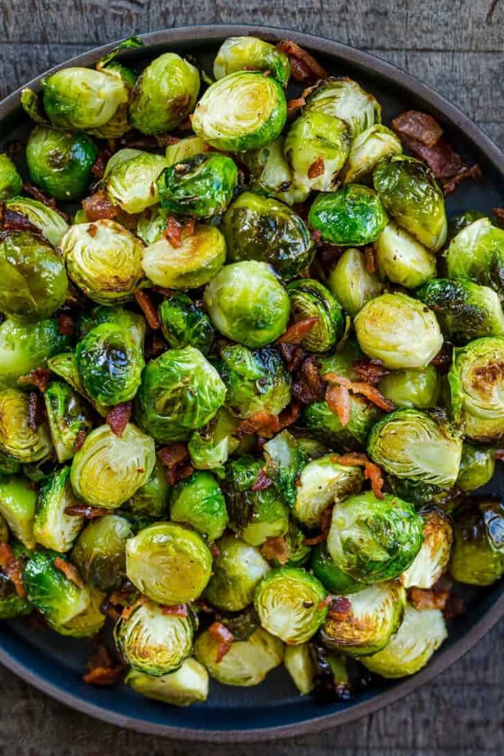 Roasted Brussels Sprouts are tender and caramelized with crisp edges. Baked Brussels sprouts are an easy, excellent side dish with just 5 ingredients. #brusselssprouts #roastedbrusselssprouts #brusselssproutsrecipe #sidedish #natashaskitchen #brusselsprouts Roasted Brussels sprouts in a bowl ready to be stored