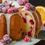 Cranberry Orange Bundt Cake on a platter with slice removed