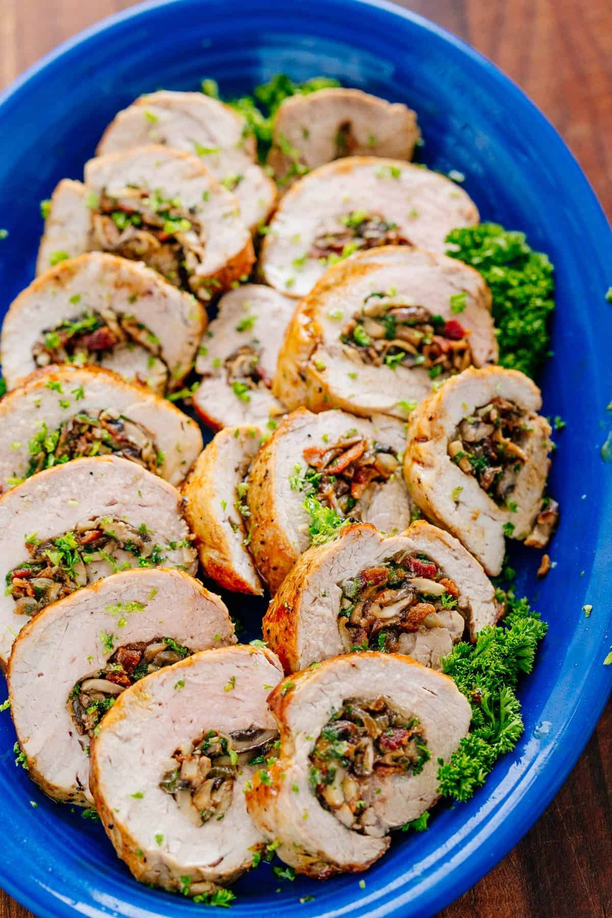 Juicy Stuffed Pork Tenderloin recipe loaded with mushrooms and bacon. With just a few ingredients, this easy pork recipe is a crowd favorite! Stuffed Pork Tenderloin sliced into rings on platter
