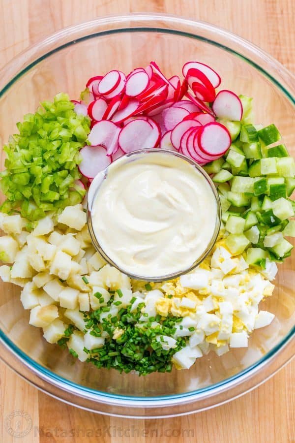 Potato Salad ingredients in a bowl with boiled potatoes, egg, cucumber, radish and celery