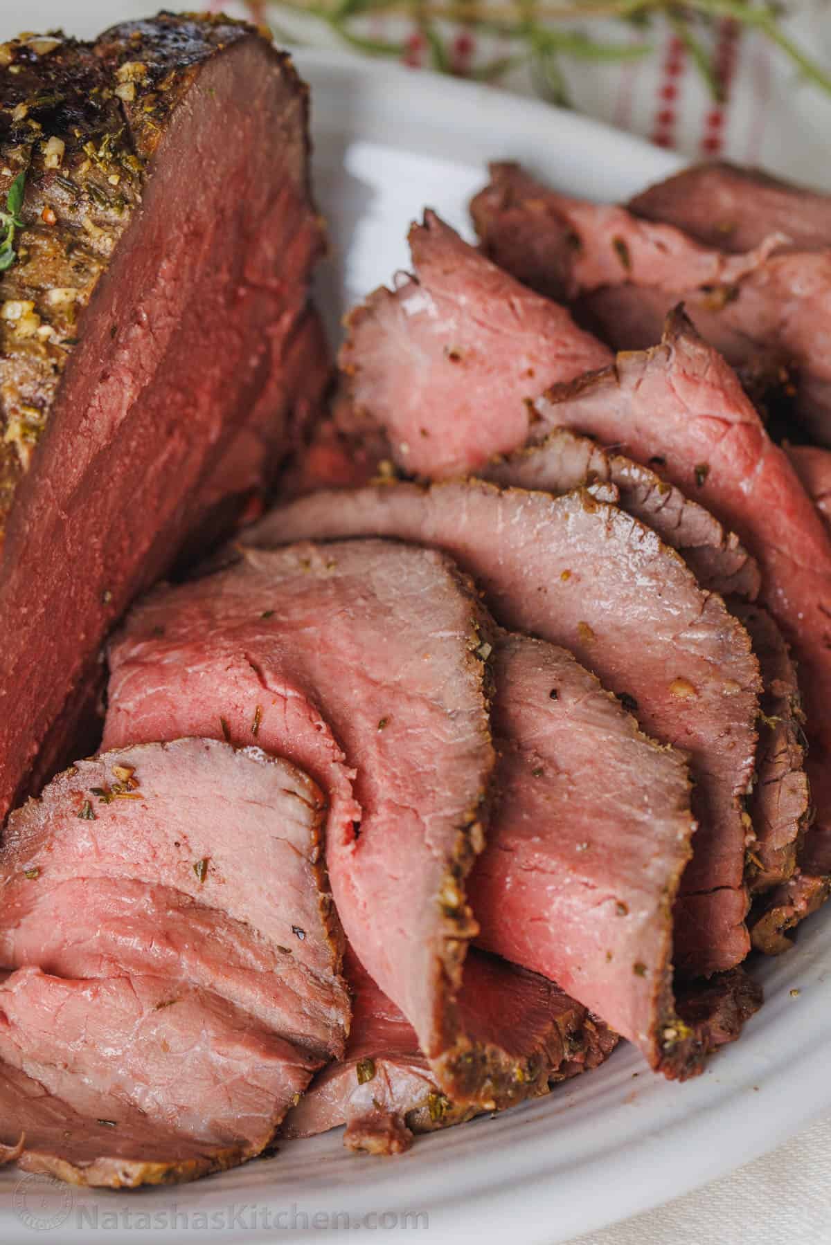 This simple, juicy Roast Beef with savory homemade pan gravy is just as impressive as any holiday roast. Every bite melts in your mouth. Close up of thin beef slices on a platter next to roast beef.
