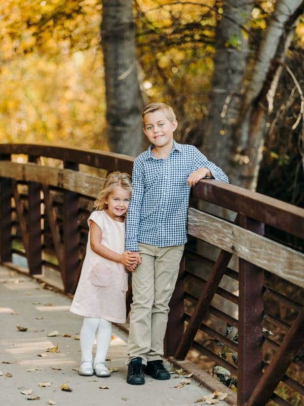 A photo of two children standing on a bridge holding hands