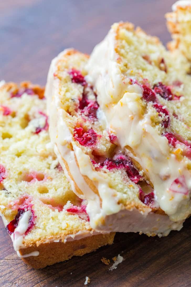 Orange-glazed Cranberry bread with a moist and tender crumb and loaded with juicy cranberries. The cranberry loaf stays moist for days. Orange glazed cranberry bread slices
