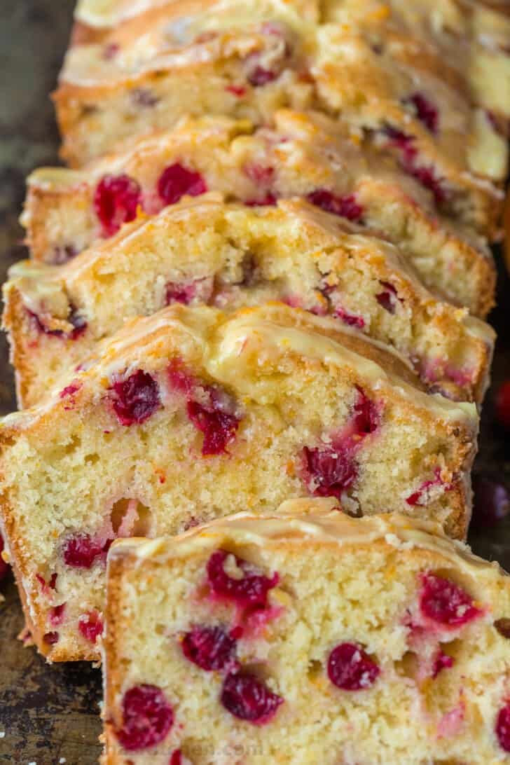 Orange-glazed Cranberry bread with a moist and tender crumb and loaded with juicy cranberries. The cranberry loaf stays moist for days. Close up slices of cranberry orange glazed bread