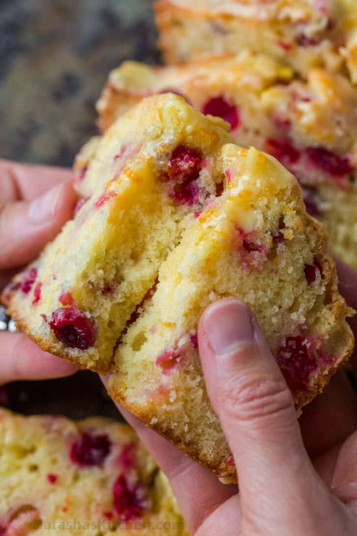 Orange-glazed Cranberry bread with a moist and tender crumb and loaded with juicy cranberries. The cranberry loaf stays moist for days. Slice of cranberry bread broken in half to show tender center