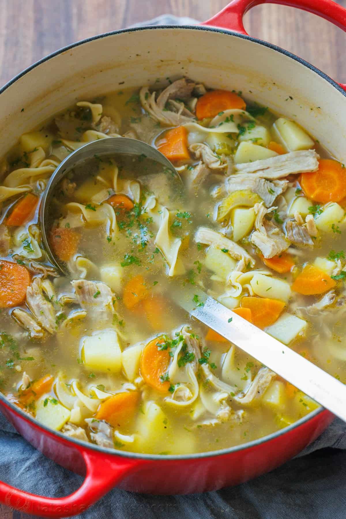 This hearty Turkey Noodle Soup recipe is warm, comforting, and simple to make. It's the perfect way to use the leftover turkey from your holiday dinners. Hearty turkey noodle soup being scooped out of a pot with a large ladle