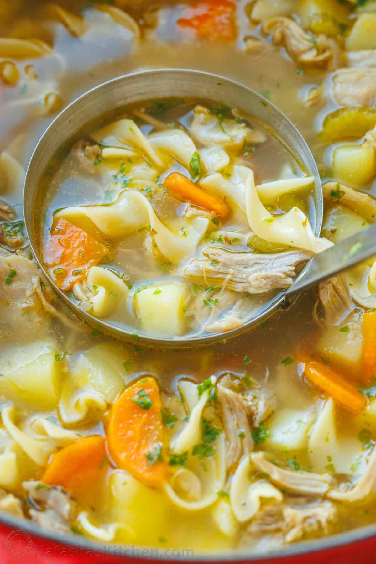 This hearty Turkey Noodle Soup recipe is warm, comforting, and simple to make. It's the perfect way to use the leftover turkey from your holiday dinners. Hearty turkey noodle soup being scooped out of a pot with a large ladle