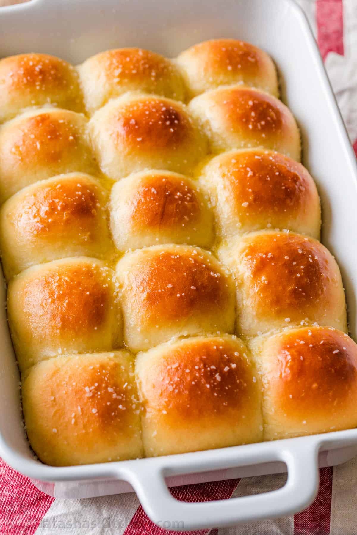 Irresistibly Soft Dinner Rolls are easy to make with just 6 ingredients. There's nothing like fluffy warm homemade dinner rolls. These are holiday worthy! #dinnerrolls #softdinnerrolls #homemadedinnerrolls #easydinnerrolls #howtomakedinnerrolls #natashaskitchen Dinner rolls in a baking sheet.