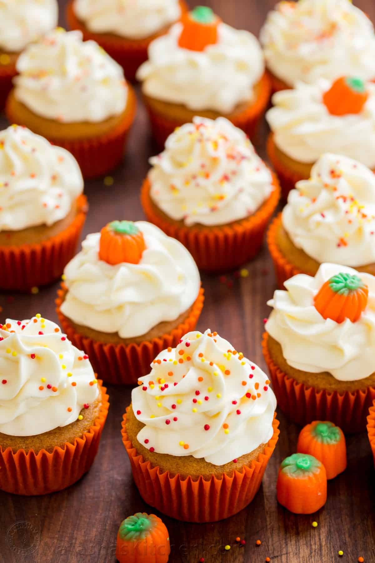 Taste the best pumpkin cupcake ever! It's a moist spiced pumpkin cupcake recipe with cream cheese frosting that bakes up quickly and easily. decorated pumpkin cupcakes in orange wrappers with pumpkin Fall decorations