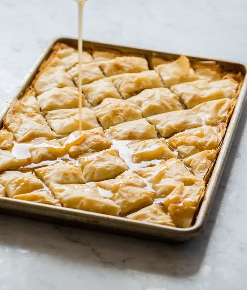 Brie Filled Baklava recipe A tray of brie filled baklava with honey being poured over the top.