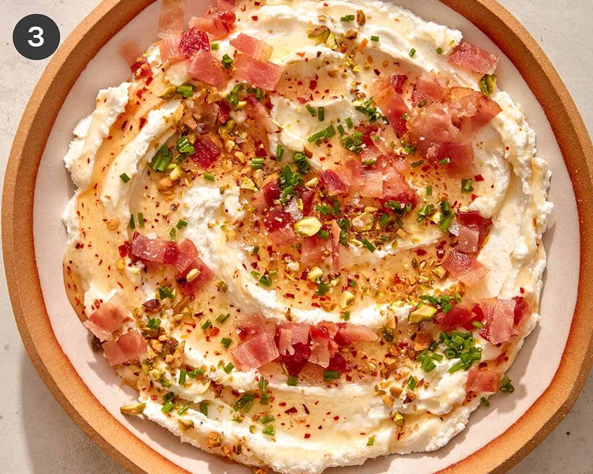 Whipped goat cheese in a bowl with toppings on top.