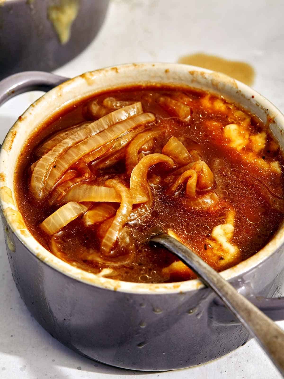 French Onion soup recipes in a bowl with a spoon in it.