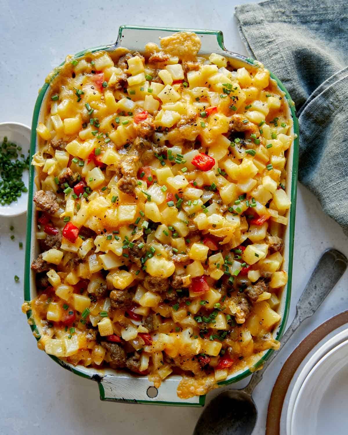 Breakfast casserole in a baking dish with a spoon next to it.