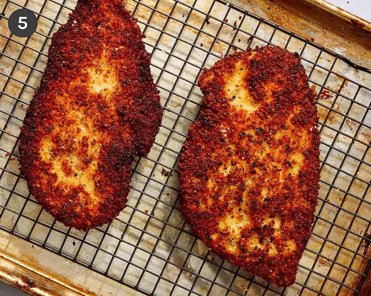 Breaded chicken breasts resting on a baking sheet.