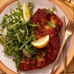 Chicken milanese recipe on two plate with forks and knives.