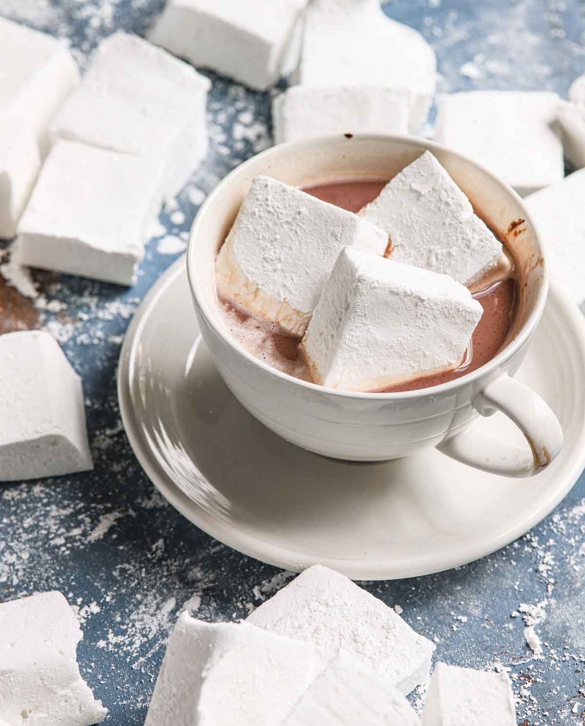 A small mug of hot chocolate with three homemade marshmallows floating on top.