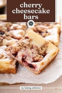 Sliced cherry cheesecake bar on a piece of parchment paper. Text overlay includes recipe name.