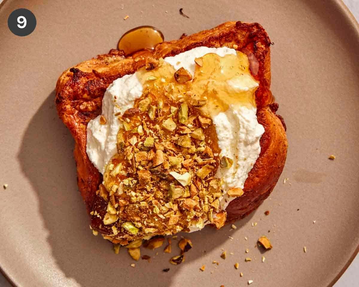 A slice of french toast topped with ricotta, nuts, and honey.