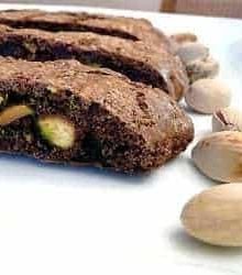 3 slices of chocolate pistachio biscotti on a white plate.