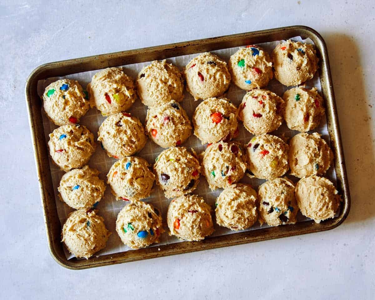 M&M Cookies on a baking sheet being refrigerated.