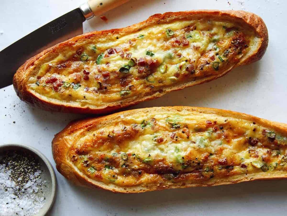 Baked egg boats on a surface with a knife.