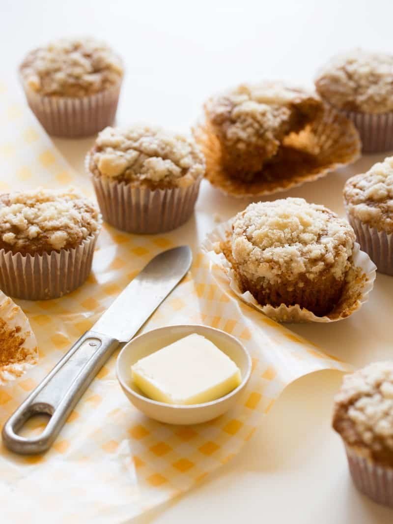 Streuseled Acorn Squash Muffins recipe Several streuseled acorn squash muffins next to a ramekin of butter and a knife.