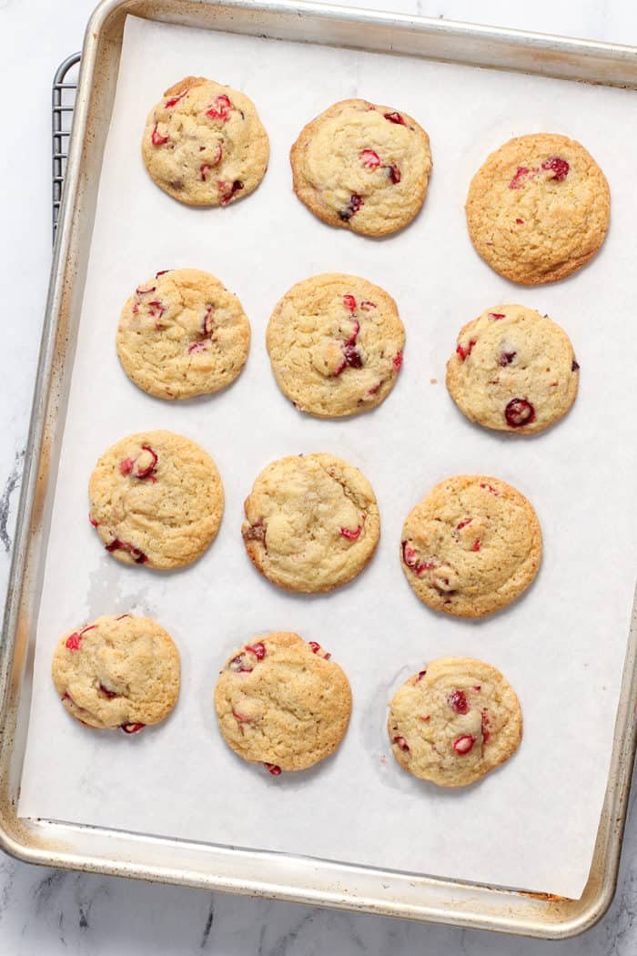 Baked orange cranberry cookies on a parchment lined baking sheet
