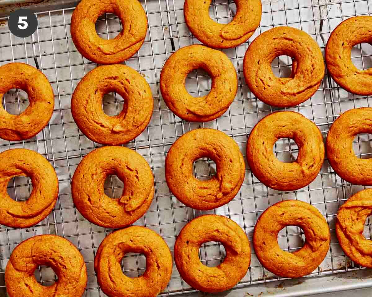 Baked pumpkin donuts being cooled on a rack. 