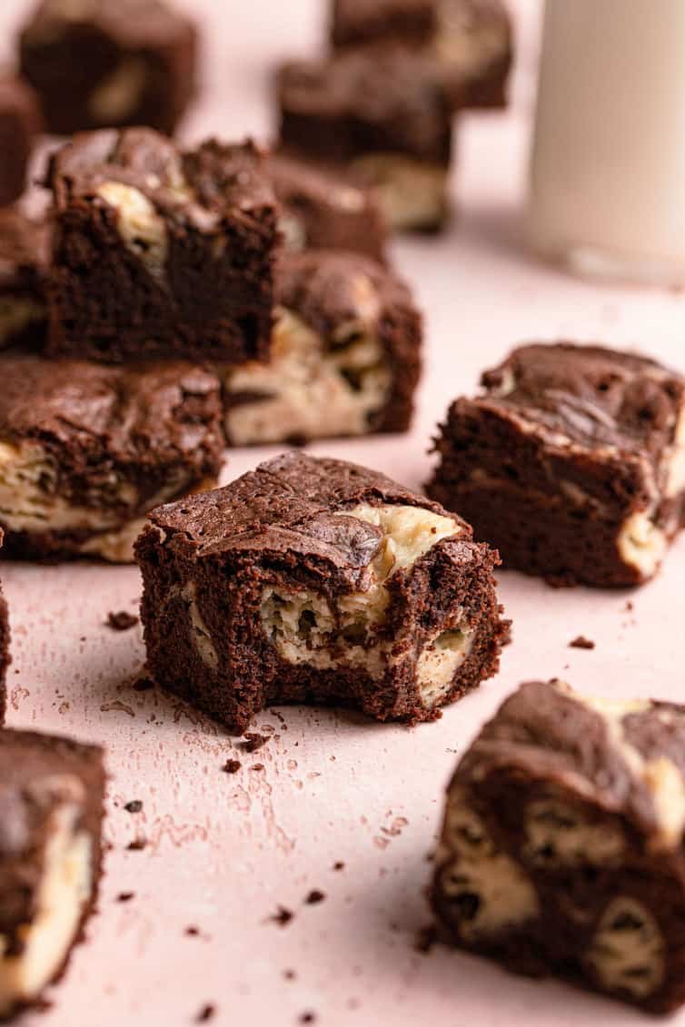 A cheesecake brownie with bite taken out, surrounded by other brownies.