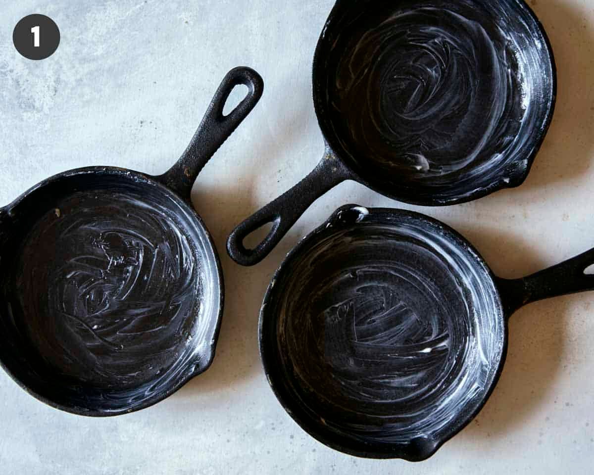 Buttered cast iron skillets to make apple crisps.
