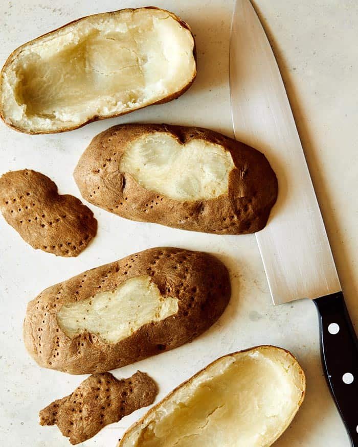 Leveling out potato halves by cutting the bottom off.
