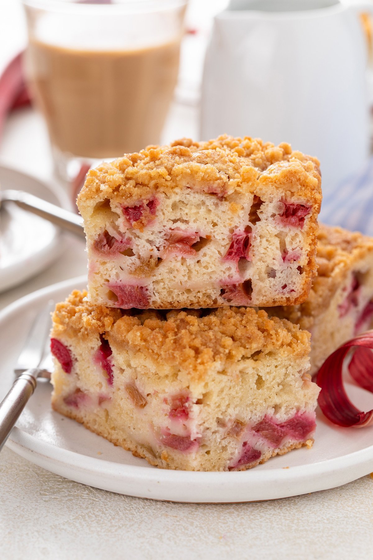 Two slices of rhubarb cake stacked on a white plate.