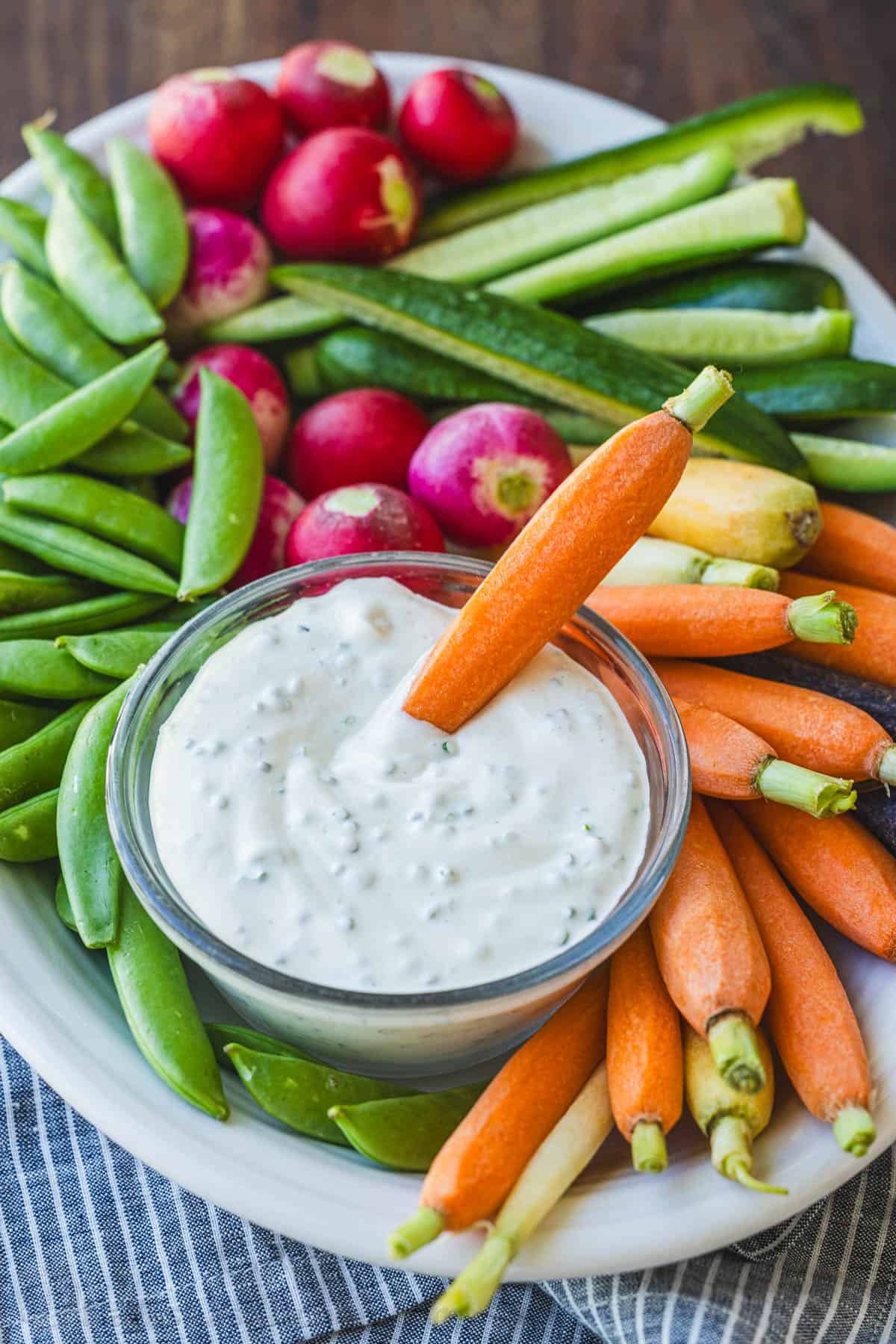 Easy Ranch Dip Recipe is ready in under 5 minutes with the best flavor and perfect thickness for dipping fresh vegetables and finger foods. Oval veggie tray with carrot dipped into sour cream dressing