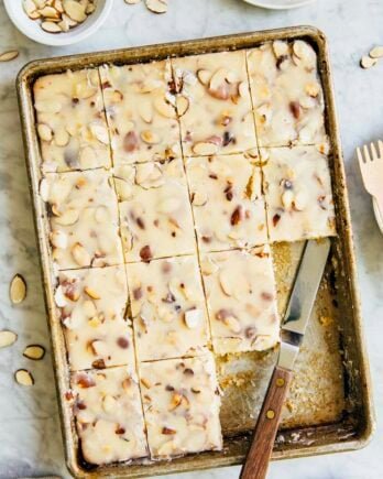 photo of a white texas sheet cake in a 9 x 13 inch pan on marble table with slices removed