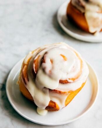 photo of a cinnamon roll with cream cheese frosting on a small white plate